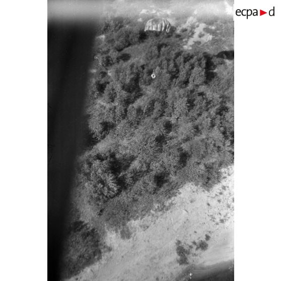 Parachutage de matériel non défini, balises ou bouées, au dessus d'un paysage rocailleux.