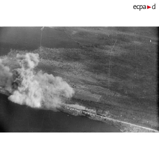 Explosions, après un bombardement, d'une voie ferrée traversant un plan d'eau.