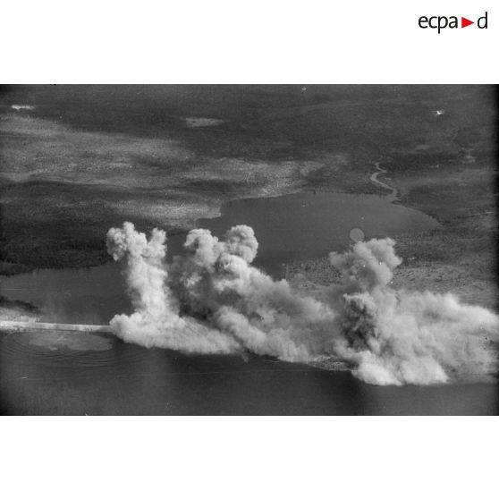 Explosions, après un bombardement, d'une voie ferrée traversant un plan d'eau.