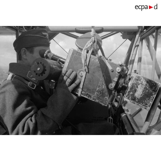 Un cameraman, membre de la 1re compagnie de propagande de l'armée de l'Air allemande (Luftwaffe Kriegsberichter Kompanie) filme le sol depuis le cockpit d'un Fi-156 Storch.