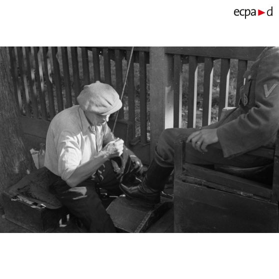 Un letton cire les bottes d'un aviateur allemand.