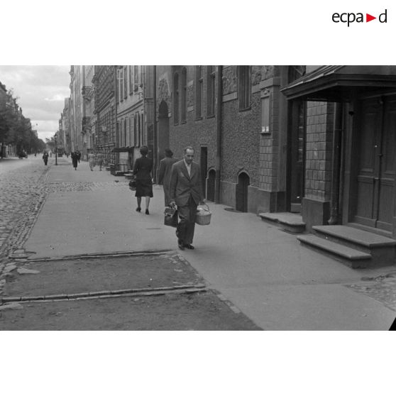 Un juif letton, marqué de l'étoile jaune, porte un panier de provisions et un porte-documents en cuir.