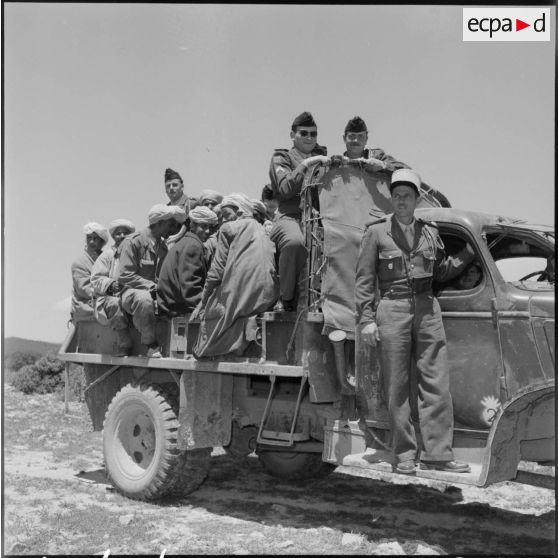 El Gor, Algérie. Des militaires de la 1re compagnie du 21e régiment d'infanterie (RI) à bord d'un camion en compagnie d'un groupe d'habitants.