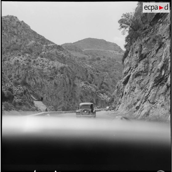 Région de Constantine. Un convoi de voitures sur une route de montagnes.