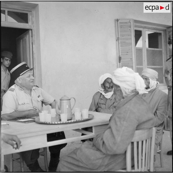 Zarouria. Un commandant du 153e régiment d'infanterie motorisée (RIM) à la terrasse d'un café avec des paysans.