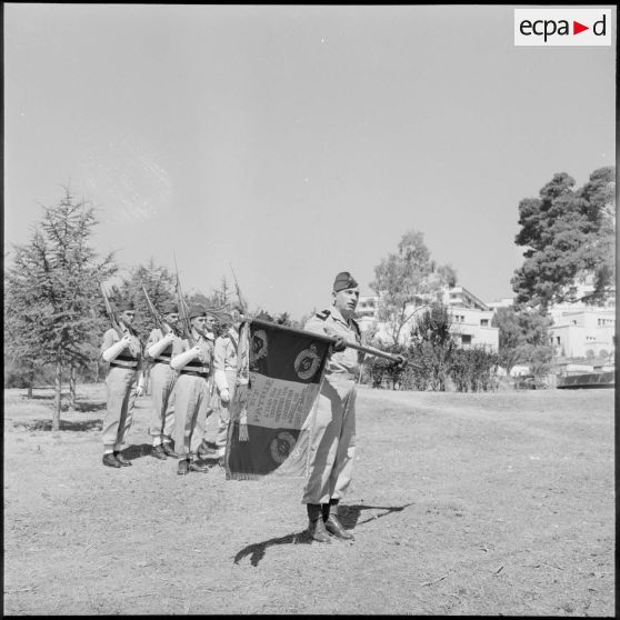 Alger, stade des Tagarins. Cérémonie du 9e régiment de zouaves (RZ) : le lieutenant-colonel André Barjaud, chef de corps du régiment, présente le drapeau aux jeunes soldats.