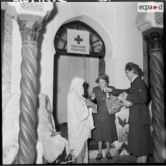 Madame Dupuis du comité d'Alger distribue du tissu et des bonbons.