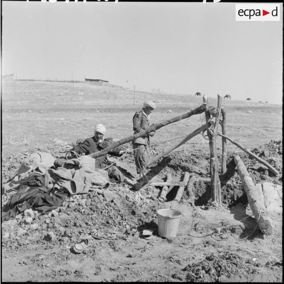 Deux habitants du village forent un puit.