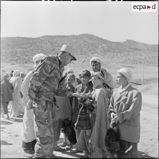 Les tirailleurs du 22ème bataillon de tirailleurs algériens se mèlent à la foule. Un enfant propose des volailles à un légionnaire.