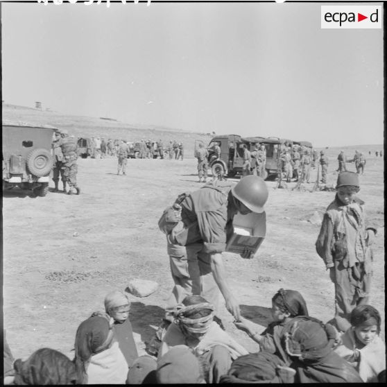 Un tirailleur qui distribue des bonbons est très entouré par les enfants.