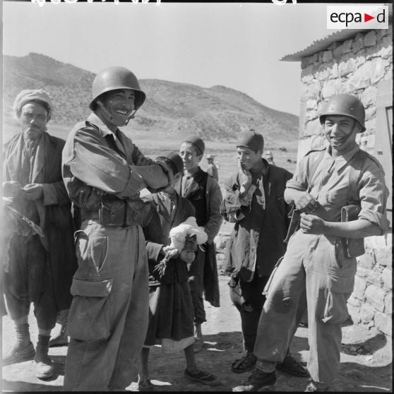 Les tirailleurs du 22ème bataillon de tirailleurs algériens se mèlent à la foule. Un enfant propose des volailles à un légionnaire.