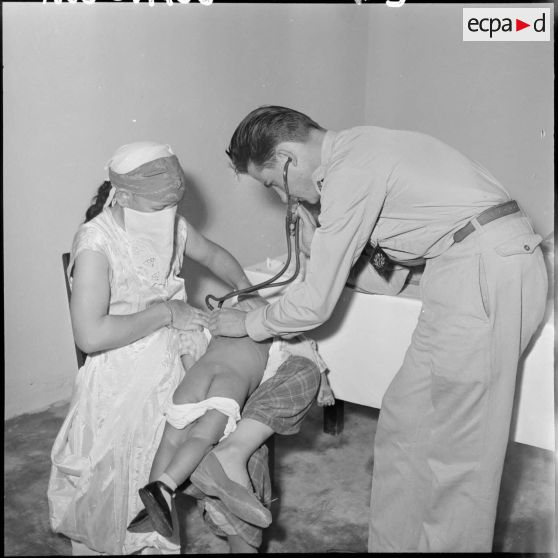 Le sous-lieutenant médecin, détaché de la 10ème division parachutiste (DP) ausculte un jeune enfant.
