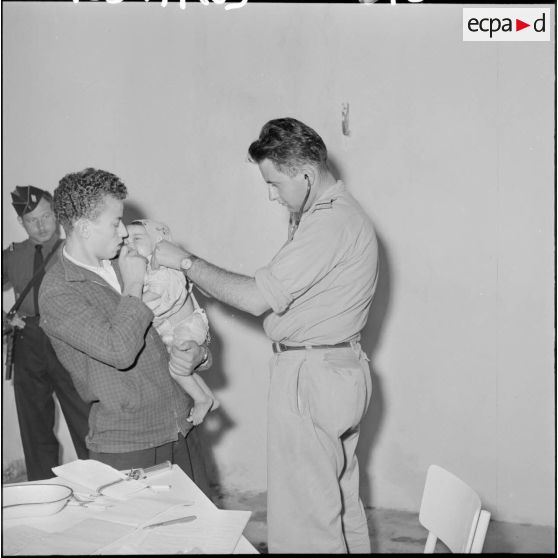 Le sous-lieutenant médecin, détaché de l'école militaire, ausculte les enfants malades.