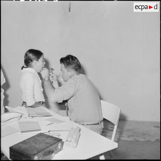 Le sous-lieutenant médecin, détaché de l'école militaire, ausculte les enfants malades.