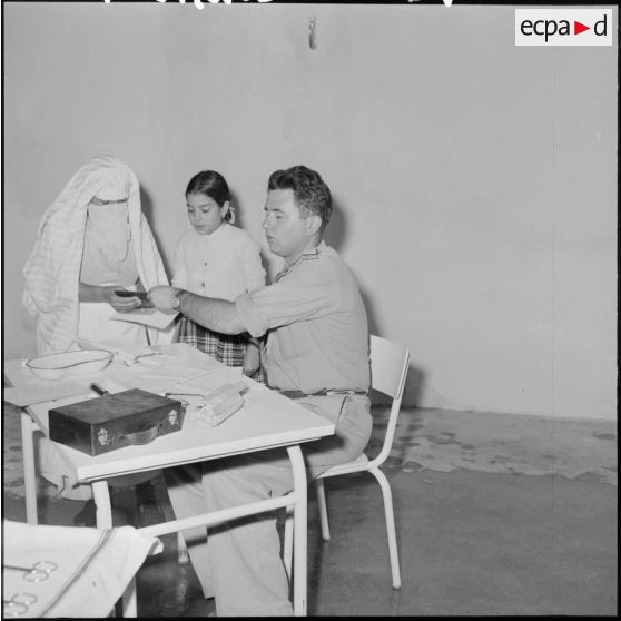 Le sous-lieutenant médecin, détaché de l'école militaire, ausculte les enfants malades.