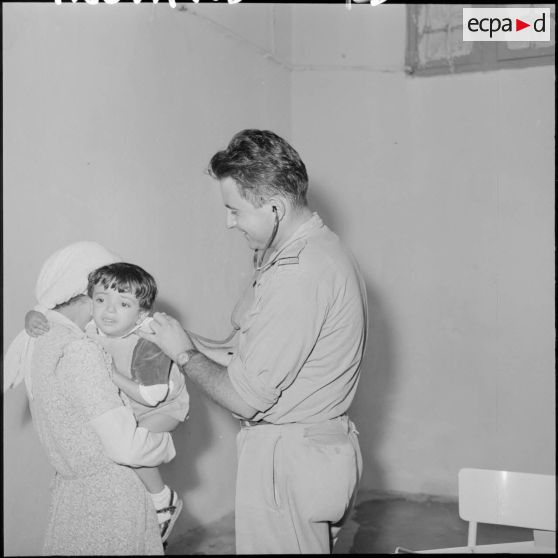 Le sous-lieutenant médecin, détaché de l'école militaire, ausculte les enfants malades.