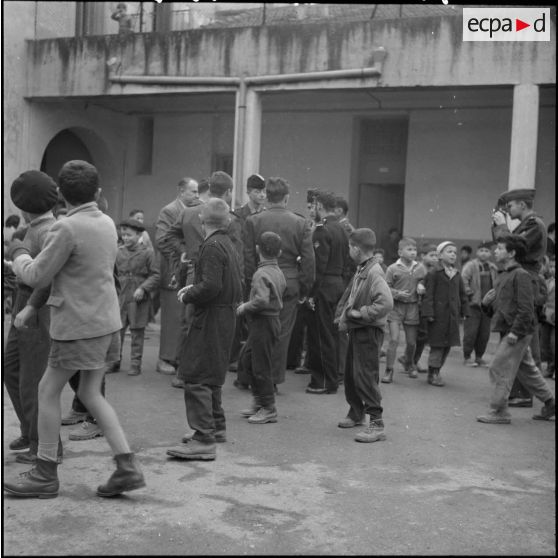 Dans la cour de l'école de Bouïra les militaires au milieu des enfants pendant la récréation.