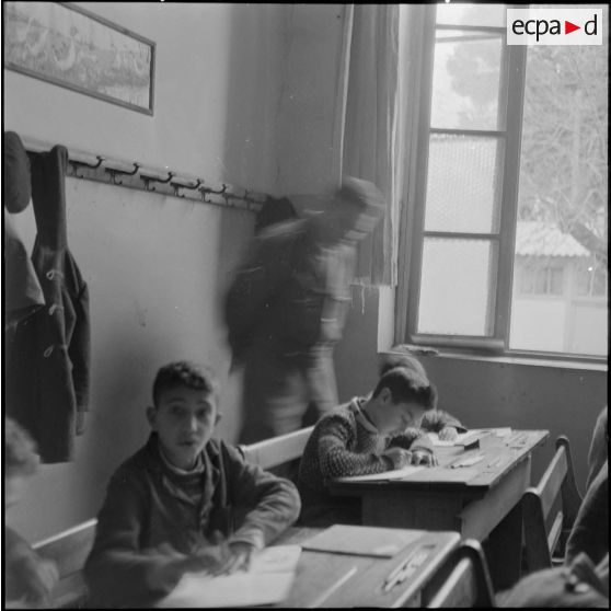 Un stagiaire militaire de l'école de Bouïa conseille des enfants pour leurs leçons.