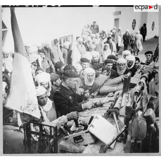 Présentation à la population d'Arris de l'armement et des trois drapeaux pris aux rebelles.