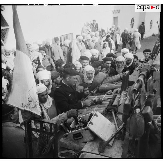 Présentation à la population d'Arris de l'armement et des trois drapeaux pris aux rebelles.