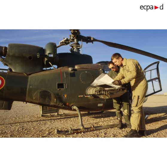 Deux pilotes de l'ALAT (aviation légère de l'armée de terre) étudient la carte avant leur départ en mission à bord d'un hélicoptère de combat Gazelle.
