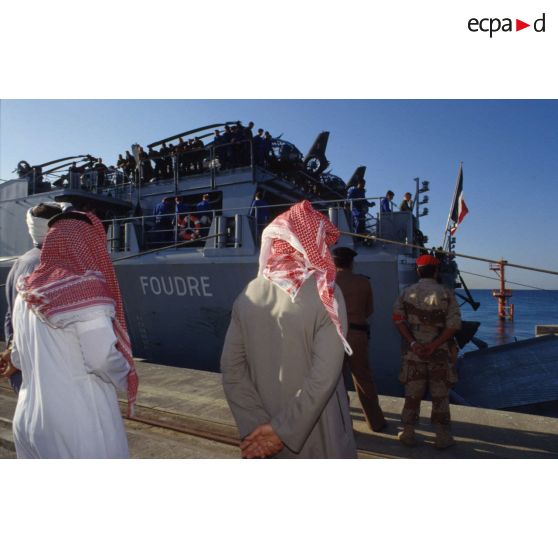 Le TCD (transport de chalands de débarquement) Foudre arrive à quai à Tanvu. La population civile suit les manoeuvres d'abaisssement de la rampe pour le débarquement.