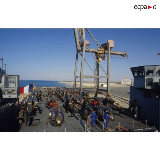 Sur la plage arrière du TCD (transport de chalands de débarquement) Foudre à quai à Yanbu sont alignés des hélicoptères de combat Gazelle de l'ALAT (aviation légère de l'armée de terre), pales repliées.
