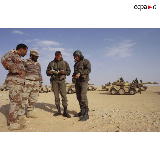 Deux soldats demandent leur route dans le désert à des militaires saoudiens, à l'aide d'un dictionnaire, pour la colonne de blindés de reconnaissance ERC-90 Sagaie du 1er RHP (régiment de hussards parachutistes).