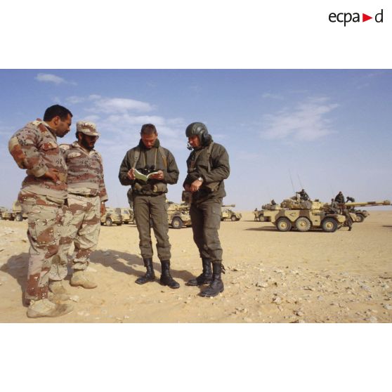 Deux soldats demandent leur route dans le désert à des militaires saoudiens, à l'aide d'un dictionnaire, pour la colonne de blindés de reconnaissance ERC-90 Sagaie du 1er RHP (régiment de hussards parachutistes).