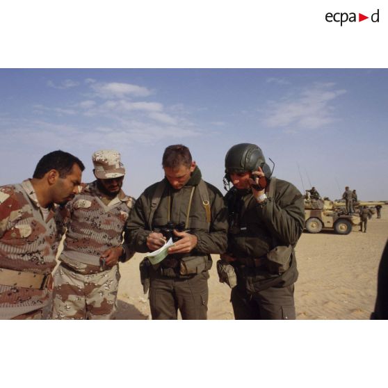Deux soldats demandent leur route dans le désert à des militaires saoudiens, à l'aide d'un dictionnaire, pour la colonne de blindés de reconnaissance ERC-90 Sagaie du 1er RHP (régiment de hussards parachutistes).