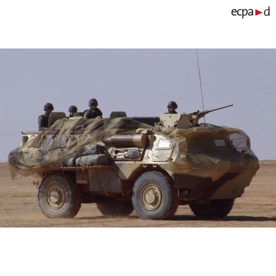 VAB à l'arrêt, recouvert d'un filet de camouflage. Le chef de tir est à son poste, derrière sa mitrailleuse de 12,7 mm.