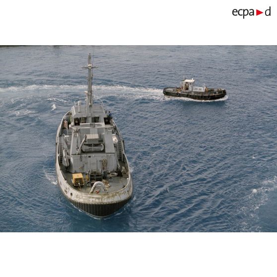 Un pousseur et un remorqueur côtier sont mobilisés pour le départ du porte-container le Rodin du port de Moruroa. [Description en cours]