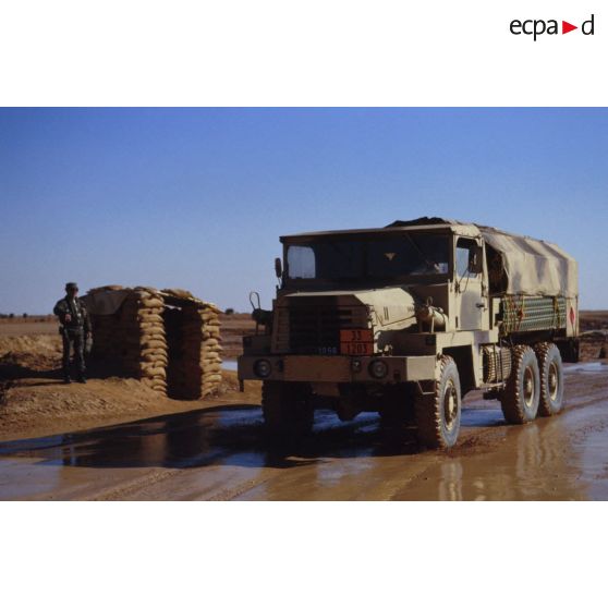 Véhicules logistiques du camp de Miramar : un camion GBC 8KT passe devant un poste de garde constitué de sacs de sable.