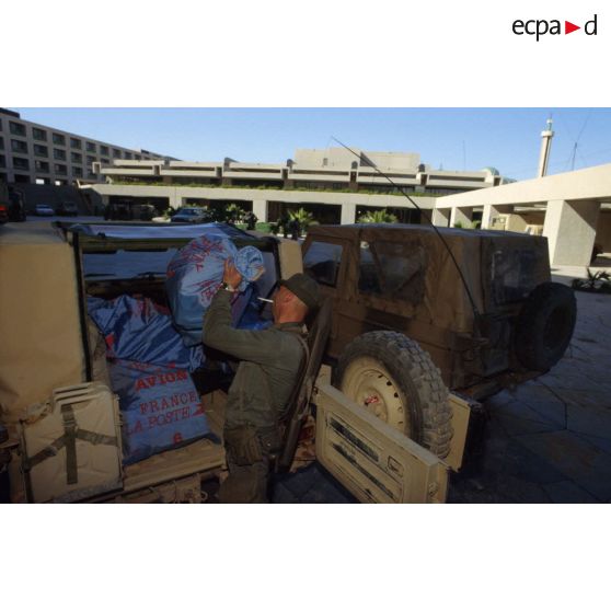 Déchargement des sacs de courrier entassés dans des véhicules Peugeot P4 par un soldat de la Poste aux armées à CRK (camp du roi Khaled).