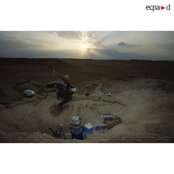 En ZDO (zone de déploiement opérationnel) Olive, trou de combat d'un soldat du 1er RS (régiment de spahis) au repos à l'aube, qui lit ou écoute la radio.