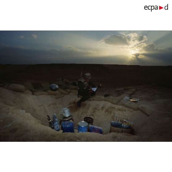 En ZDO (zone de déploiement opérationnel) Olive, trou de combat d'un soldat du 1er RS (régiment de spahis) au repos à l'aube, qui lit ou écoute la radio.