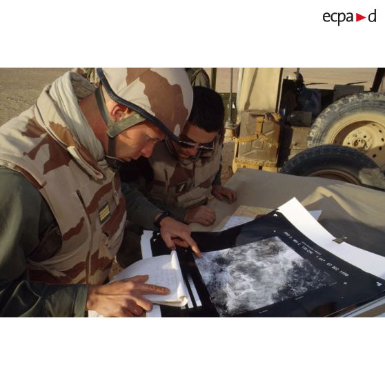 En ZDO (zone de déploiement opérationnel) Olive, un capitaine français géographe présente l'agrandissement d'une photographie aérienne de la région prise par le satellite français SPOT à un officier américain.