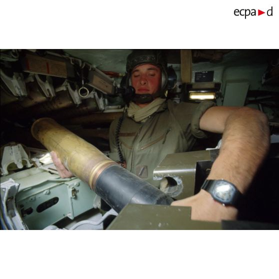 En ZDO (zone de déploiement opérationnel) Olive, le pourvoyeur manipule un obus de 105 mm dans un char lourd de combat AMX-30 B2 du 4e RD (régiment de dragons).