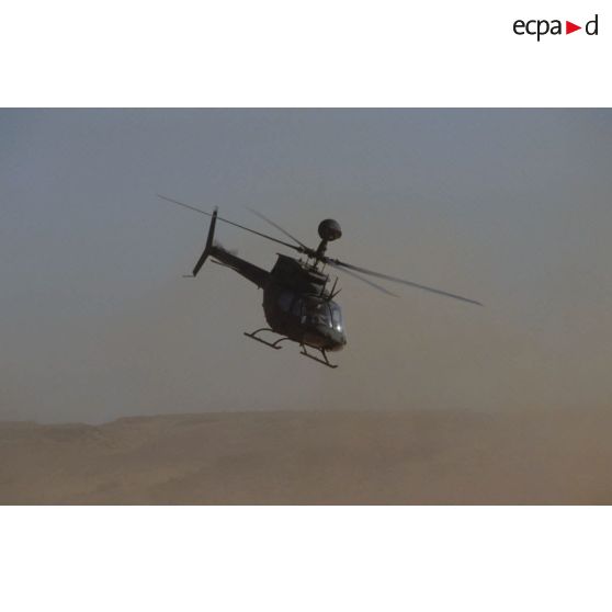 Aux alentours du CRK (camp du roi Khaled), un hélicoptère de reconnaissance et d'observation Bell-OH58 Kiowa muni d'un système de visée installé au-dessus du rotor en vol.