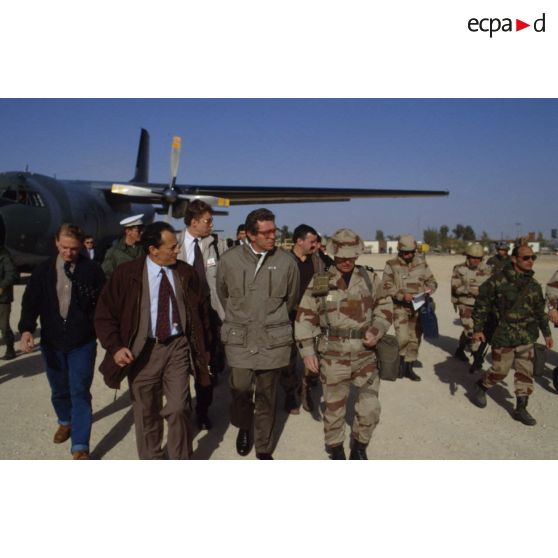 Michel Rocard, Premier ministre, et Pierre Joxe, ministre de la Défense, s'éloignent de l'avion en compagnie du général de corps d'armée Michel Roquejeoffre, commandant en chef de l'opération Daguet, entourés de personnalités civiles, militaires et de journalistes.
