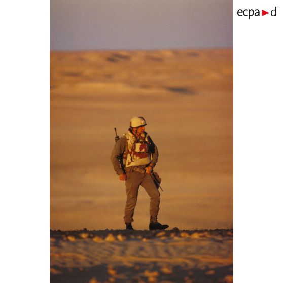 En ZDO (zone de déploiement opérationnel) Olive, un soldat est posté en observation dans le désert, équipé de jumelles.