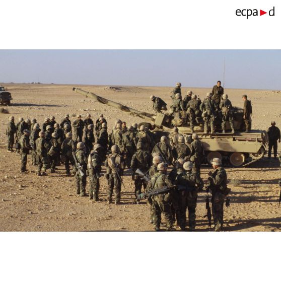 En ZDO (zone de déploiement opérationnel) Olive, un groupe de sodats américains entourent ou sont juchés sur un char lourd de combat AMX-30 B2.