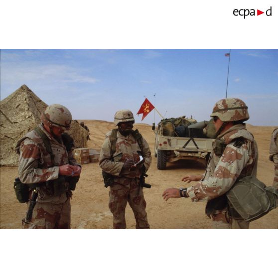 En ZDO (zone de déploiement opérationnel) Olive, au bivouac d'une batterie du 8e régiment d'artillerie américain, trois soldats discutent.
