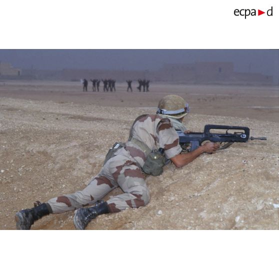 Aux abords d'Al Salman, tandis que des soldats irakiens mains en l'air se rendent, un soldat du 3e RIMa (régiment d'infanterie de marine) est posté en position de tireur couché, armé d'un FAMAS.