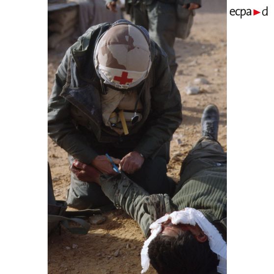 Un médecin du 3e RIMa (régiment d'infanterie de marine) soigne, sur le champ de bataille, un soldat irakien blessé au crâne et aux bras.