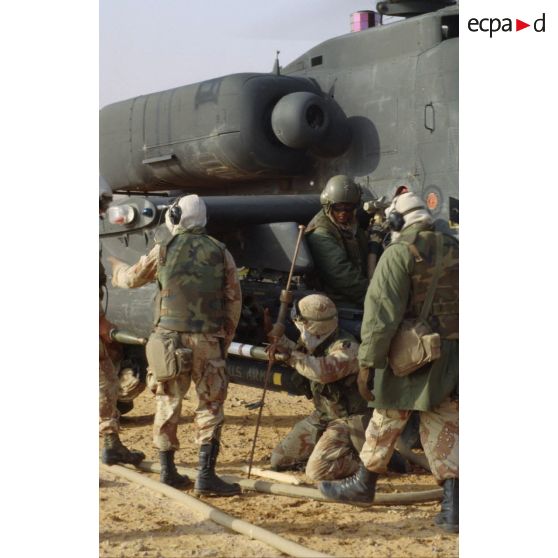 En ZDO (zone de déploiement opérationnel) Olive, des soldats approvisionnent un panier de roquettes de 70 mm d'un hélicoptère de combat américain Hughes-AH 64 Apache de retour de mission.