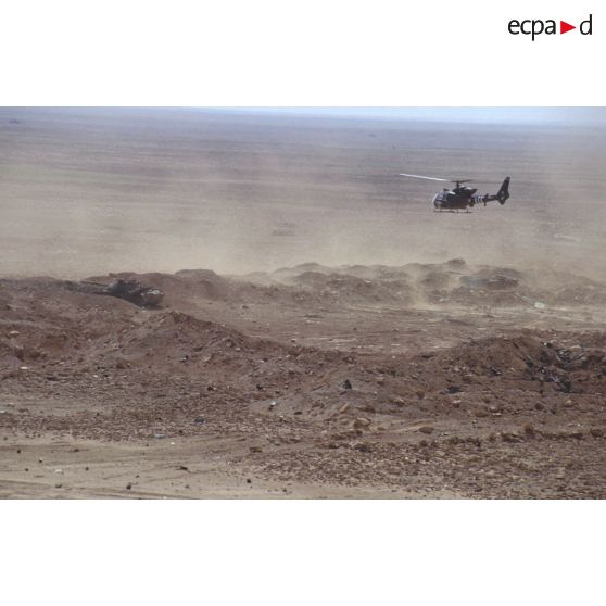 Survol par un hélicoptère Gazelle d'une position fortifiée irakienne, d'un char de combat T-55 et d'un transport de troupes chenillé MT-LB irakiens détruits dans la zone de Rochambeau.