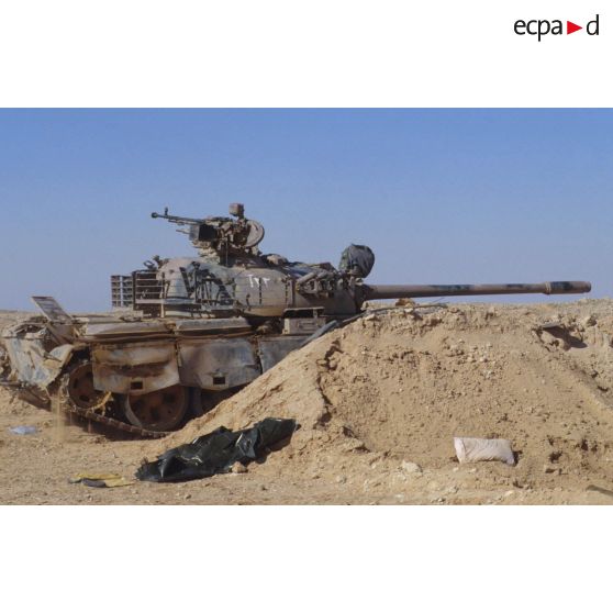Un char de combat T-55 irakien, armé d'un canon antichar D-10T2S de 100 mm et d'une mitrailleuse lourde DShKMT de 12,7 mm, protégé par un merlon de sable vers l'avant.