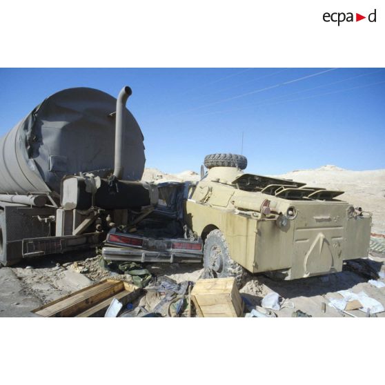 Blindés et camions irakiens détruits ou abandonnés à la sortie de Koweit City : un blindé de reconnaissance BRDM-2, une voiture et un camion-citerne encastrés.