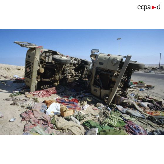 Epaves de camions irakiens détruits à la sortie de Koweit City, au milieu de tissus jonchant le sol.